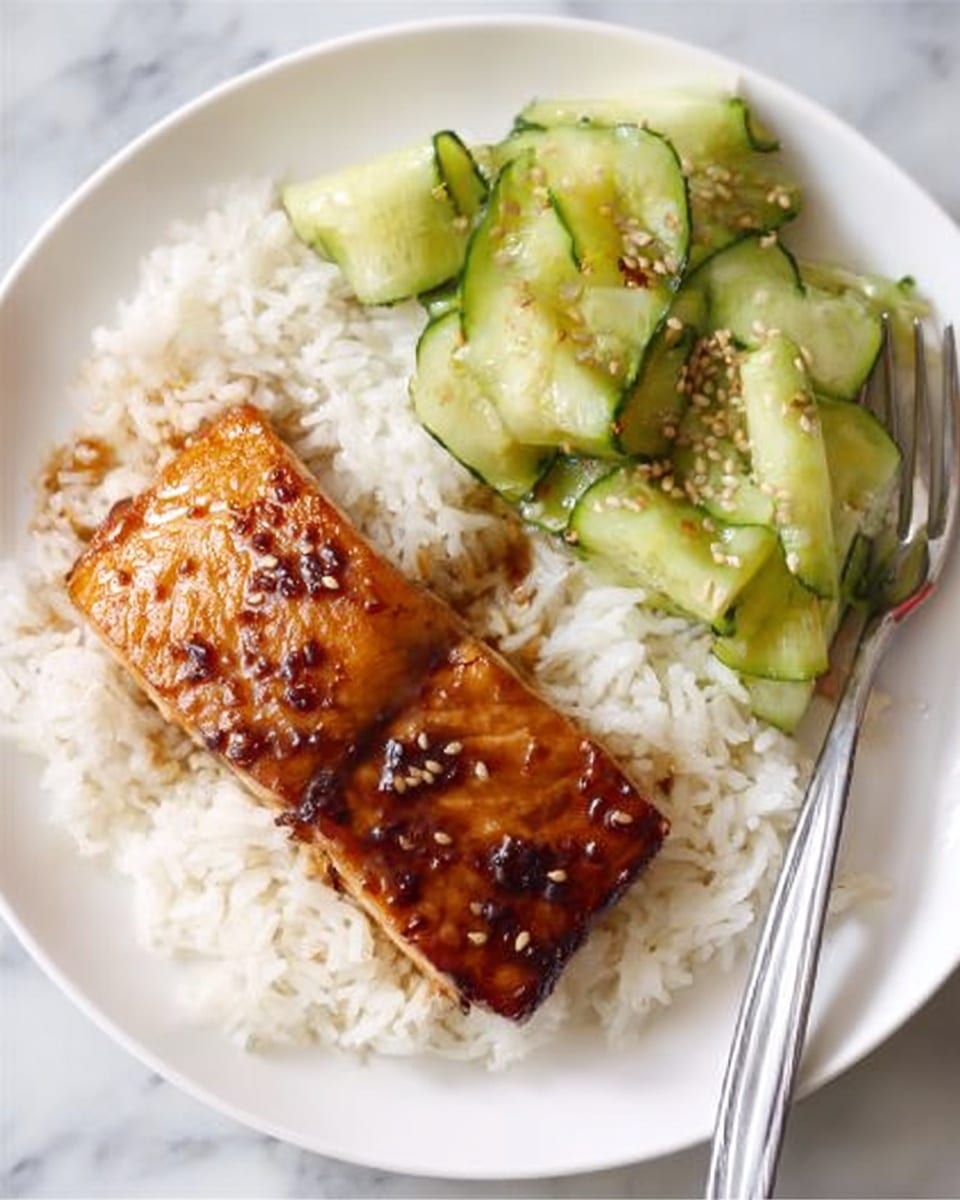 A white plate with a layer of fluffy white rice at the bottom right, next to a block of grilled salmon with a shiny, golden-brown glaze on top and a few sesame seeds scattered, covering the middle left side of the plate. On the upper right, there are light green ribbons of cucumber with a slight gloss and sesame seeds sprinkled on them. A silver fork rests on the right edge of the plate. The setting is on a white marbled surface. Photo taken with an iphone --ar 4:5 --v 7