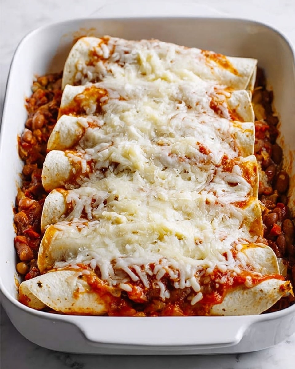 The image shows a white rectangular dish filled with three rolled tortillas placed side by side. The tortillas are topped with a thick layer of chunky tomato sauce mixed with beans and pieces of vegetables, giving a reddish-brown color and a textured look. On top, there is a generous layer of melted white cheese, with slightly browned spots from baking, covering most of the sauce. The dish is set on a white marbled surface, creating a clean and bright background. photo taken with an iphone --ar 4:5 --v 7