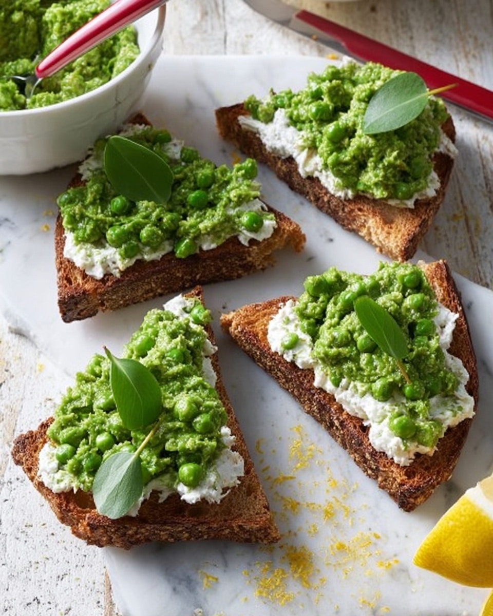 The image shows four triangular pieces of toasted bread with a crispy brown crust placed on a white marbled surface. Each toast has a thick layer of white creamy spread topped with a chunky green pea mash, rich in texture and color. Small green leaves are placed on top of the mash on some pieces, adding a fresh look. A white bowl with more green mash and a red spoon is visible in the background, alongside part of a lemon with some zest scattered nearby. Photo taken with an iphone --ar 4:5 --v 7