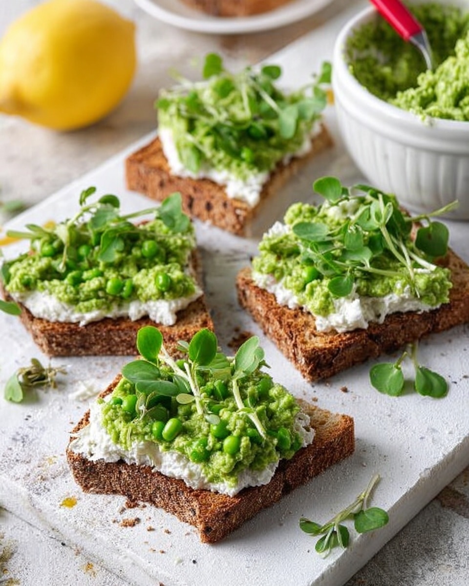The image shows four pieces of toasted brown bread with a rough, crunchy texture, each topped with a layer of white creamy spread and a generous dollop of chunky green pea mash. Fresh green pea shoots are placed on top of the mash, adding a delicate touch. The bread pieces are arranged on a white marbled surface, with a yellow lemon on the side and some scattered pea shoots around. In the background, there is a white bowl filled with more green pea mash and a red spoon resting in the bowl. Photo taken with an iphone --ar 4:5 --v 7