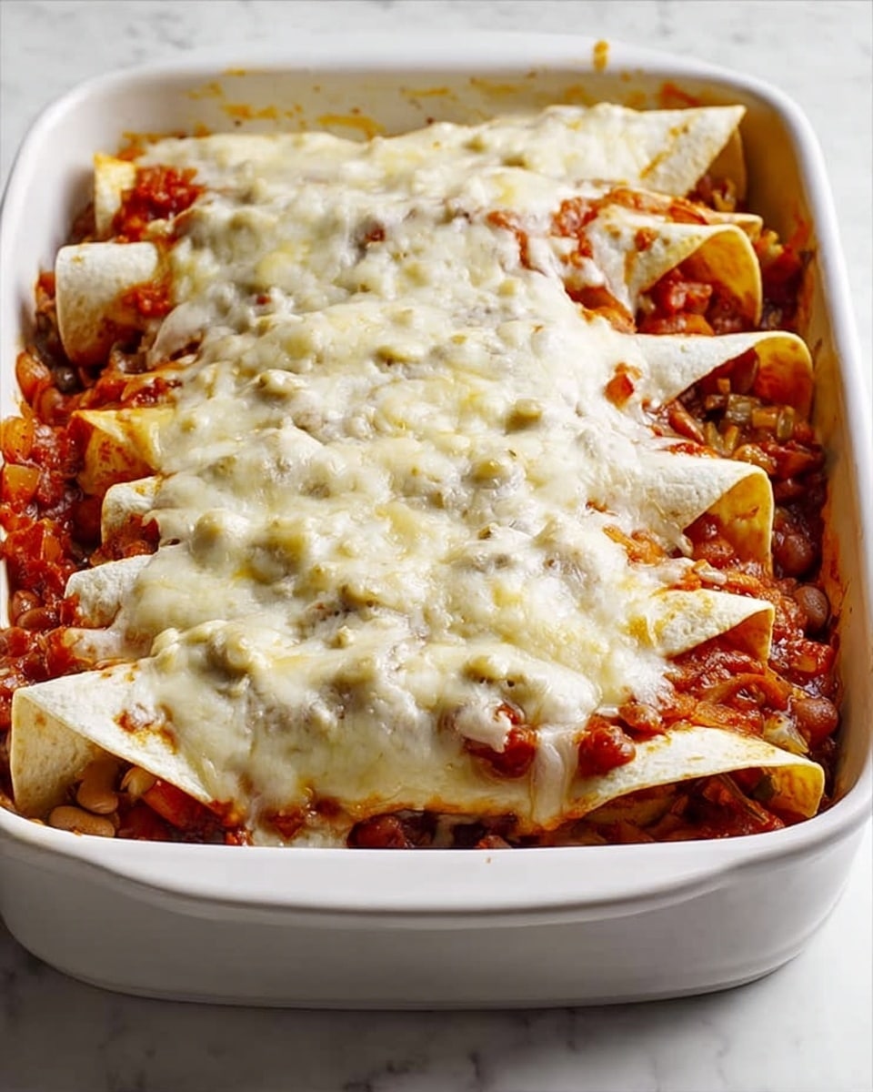 The image shows a white rectangular baking dish filled with rolled tortillas layered with a chunky mix of cooked beans and tomato sauce, with visible bits of onion and peppers throughout. On top, there is a thick layer of melted white cheese, slightly browned and bubbly, covering the filling and rolling edges. The dish sits on a white marbled surface, and the scene is softly lit, highlighting the textures of the soft tortillas, thick sauce, and gooey cheese. Photo taken with an iphone --ar 4:5 --v 7