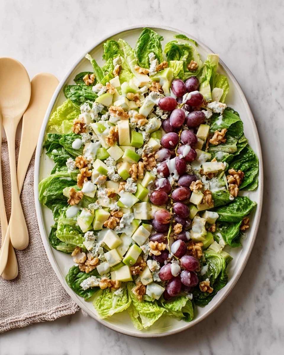 A white oval plate holds a fresh salad arranged in two layers: the bottom layer consists of large, bright green romaine lettuce leaves spread out evenly, creating a leafy base. The second layer is a mix of diced pale green apples, sliced light green celery, halved deep purple grapes, and small chunks of light brown walnuts sprinkled on top. A light creamy dressing is drizzled over the salad, adding a glossy texture to the mix. The plate is set on a surface with a white marbled texture. photo taken with an iphone --ar 4:5 --v 7