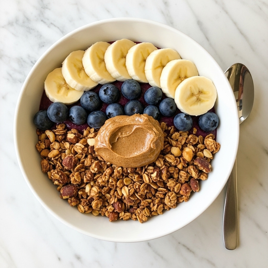 A white bowl holds a layered breakfast dish. The bottom layer is a bed of granola with a crunchy texture and shades of brown. On top of the granola, there is a neat row of round, light yellow banana slices with a soft look placed on one side. Next to the banana slices, there is a small bunch of dark blue shiny blueberries creating a contrast. In the middle, a thick dollop of smooth, dark chocolate spread sits on top of the granola. The bowl rests on a wooden surface, with a spoon resting on the edge. Photo taken with an iphone --ar 4:5 --v 7