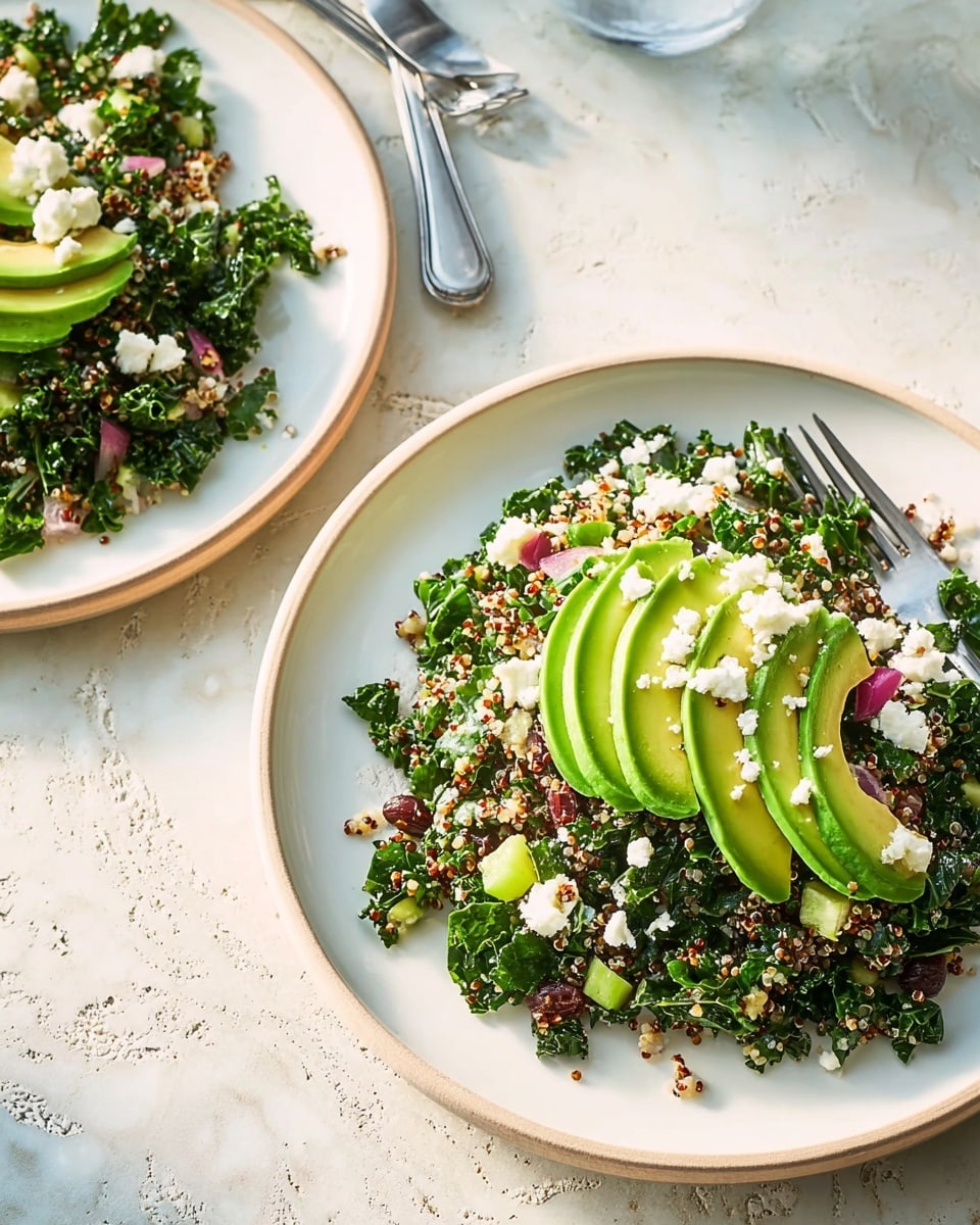 A white plate holds a fresh salad with multiple layers: the base layer is a mix of finely chopped kale, light yellow quinoa, diced green celery, and small pieces of red onion, all mixed evenly. Dark brown raisins are scattered throughout this mixture. On top of the salad, there are two sections of sliced avocado, bright green and smooth in texture, neatly laid in the center. White crumbled cheese is sprinkled over the avocado and salad, adding contrast. A metal fork rests on the edge of the plate. The background is a white marbled textured surface. photo taken with an iphone --ar 4:5 --v 7