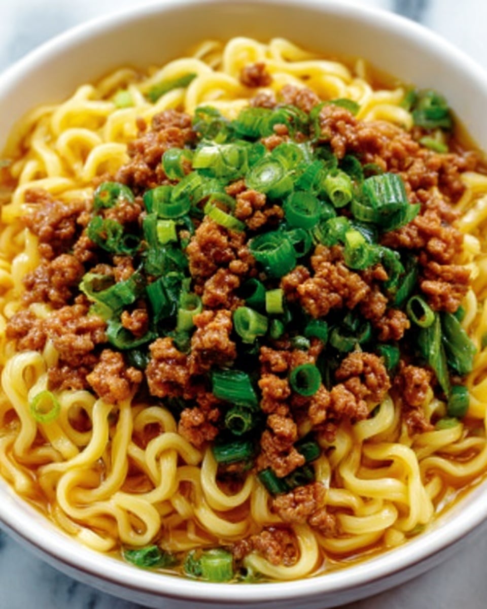 The dish shows a close-up of cooked noodles topped with a generous layer of minced meat that looks moist and brown. On top of the meat, there is a layer of chopped green onions, bright green and fresh-looking, creating a nice color contrast. The noodles are thick and yellowish, slightly shiny, and sit under the toppings. All of this is presented in a white bowl, placed on a white marbled surface. Photo taken with an iphone --ar 4:5 --v 7